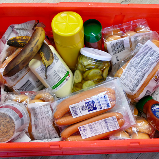 In einer roten Kiste, die auf dem Fußboden steht, liegen diverse Lebensmittel, die aus einer Biotonne gerettet worden sind.