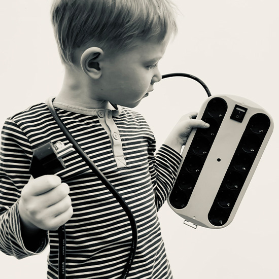 Junge hält Steckerleiste mit Schalter in der Hand